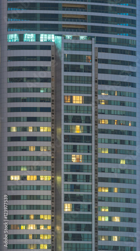 windows of office buildings illuminated at night for background