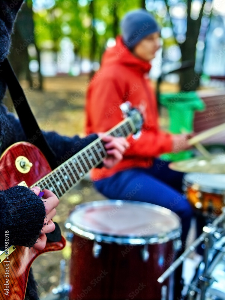 Male buskers on autumn outdoor play guitar. Cool weather.