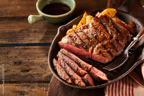 Foto Cast iron plate with sliced grilled rib-eye steak on table