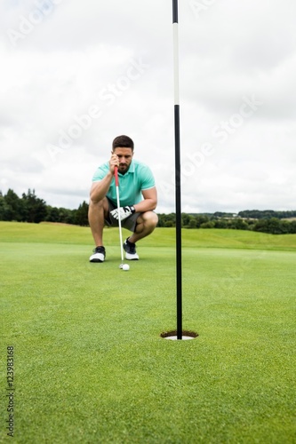 Quadro em tela Man squatting to line up his putt