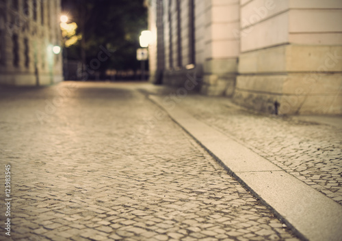 empty brick road at night with blurred background, vintage filtered style, historic midtown of Berlin, Germany, Europe