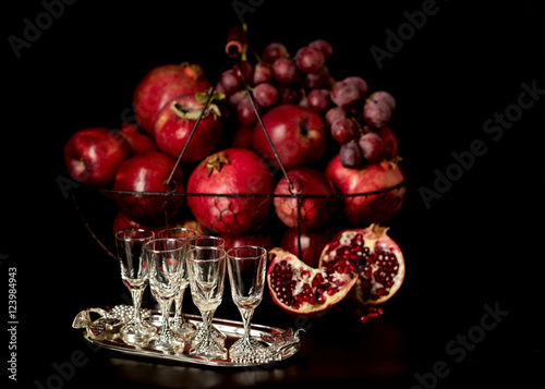 Still life on a dark background. Wine (liquor) glasses, fruits a