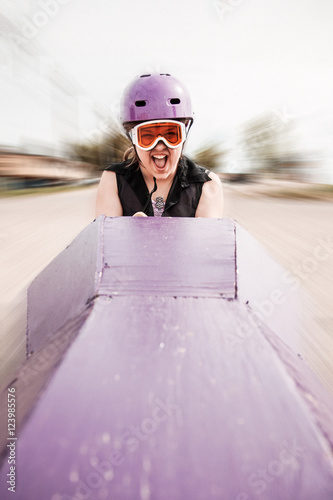 Young girl screaming as she's rolling down a hill in a soapbox car
