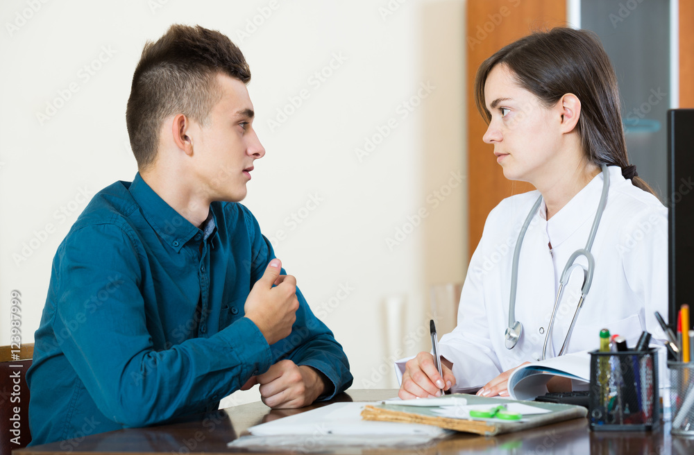 doctor receiving and questioning teen patient at office