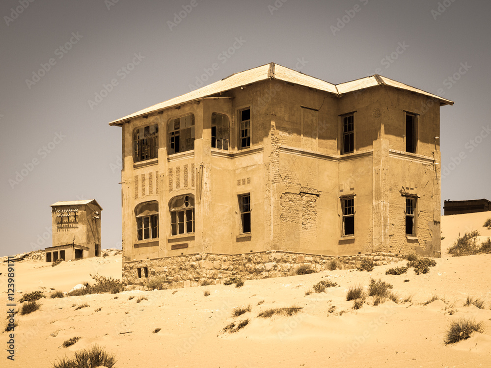 Ghost buildings of old diamond mining town Kolmanskop near Luderitz in Namibia. Abandoned house ruins sunken in the sand dunes of Namib Desert. Vintage toning photography. Ghost buildings of old diamond mining town Kolmanskop near Luderitz in Namibia. Abandoned house ruins sunken in the sand dunes of Namib Desert. Vintage toning photography.