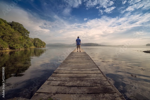 Man on a wooden footbridge in the middle of nature and the sea 