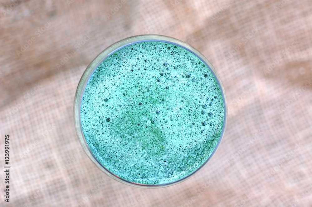 Healthy fresh smoothie drink from red apple, green algae spirulina, lemon, and celery in the glass on brown background Healthy fresh smoothie drink from red apple, green algae spirulina, lemon, and celery in the glass on brown background