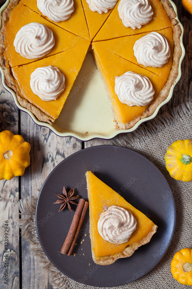 Thanksgiving homemade pumpkin pie with whipped cream and spices on rustic background, top view. Autumn Decoration and rustic style. Thanksgiving homemade pumpkin pie with whipped cream and spices on rustic background, top view. Autumn Decoration and rustic style.