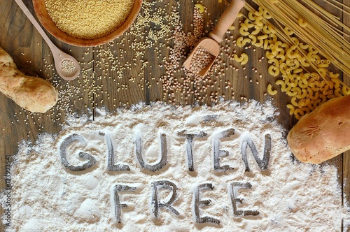Gluten free cereals corn, rice, buckwheat, quinoa, millet, pasta and flour with text gluten free on brown wooden background