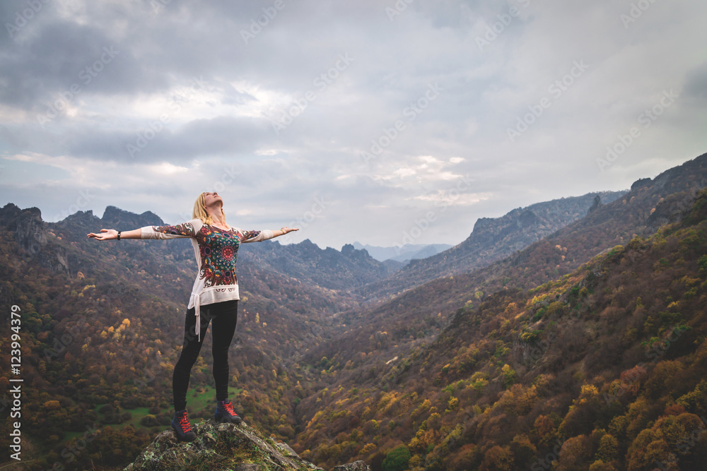Woman standing on a mountain autumn trail with raised hands, Successful feeling concept