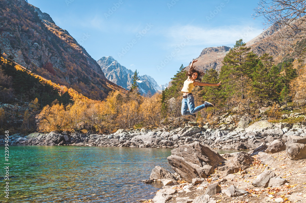 Happy Woman jumping near lake and mountains
