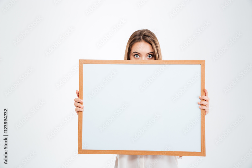 Young woman with eyes wide open peeping from blank board Young woman with eyes wide open peeping from blank board