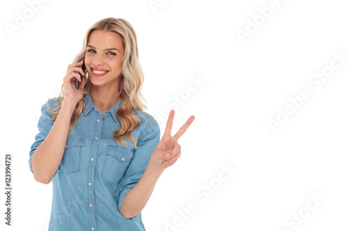 blonde woman talking on  phone and making the victory sign
