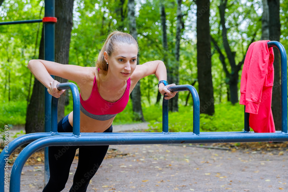 Fototapeta premium Young slim woman doing workout in a training ground in a park