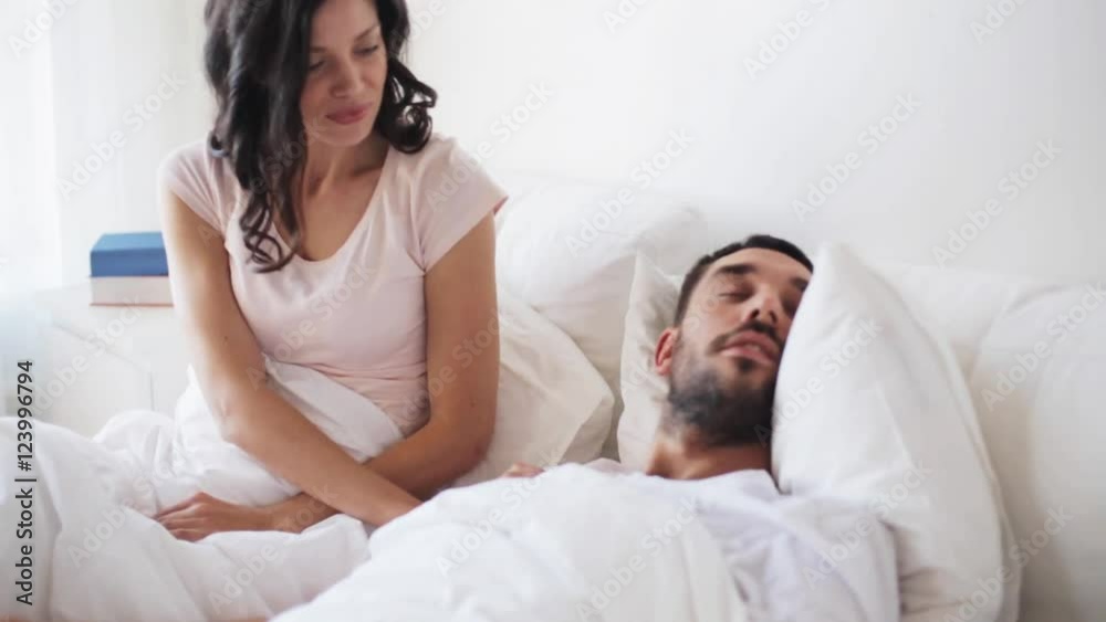angry woman waking man sleeping in bed