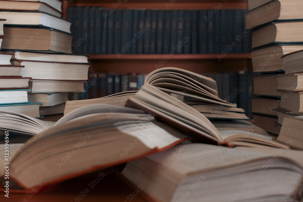Naklejka premium A stack of many old books on the table-background of bookshelve