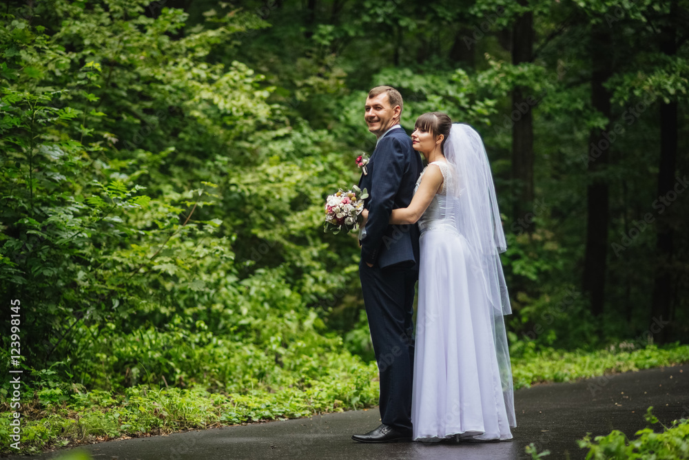 Bride and groom at wedding day, walking outdoor at summer on nature. Bridal couple, happy newlywed woman and man embracing. Loving wedding couple outdoor. Bride and groom at wedding day, walking outdoor at summer on nature. Bridal couple, happy newlywed woman and man embracing. Loving wedding couple outdoor.