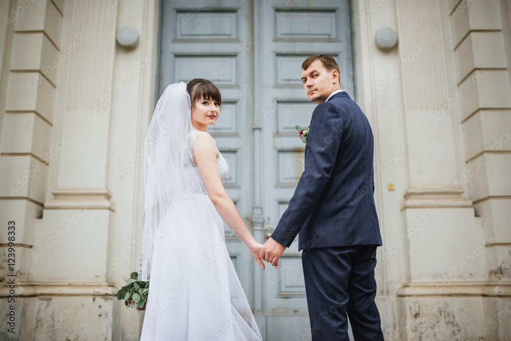 Bride and groom at wedding Day walking Outdoors near architecture. Bridal couple, Newlywed woman and man embracing with love