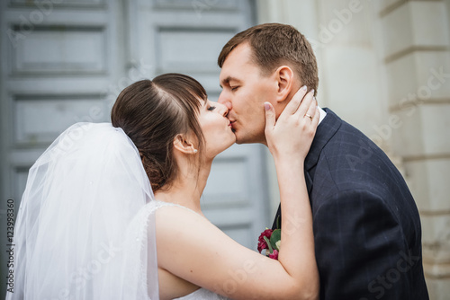 Bride and groom at wedding Day walking Outdoors near architecture. Bridal couple, Newlywed woman and man embracing with love