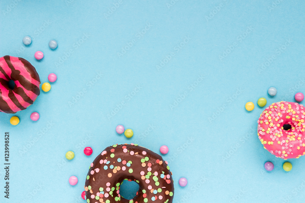 Sweet donuts with colorful candies on the blue background.