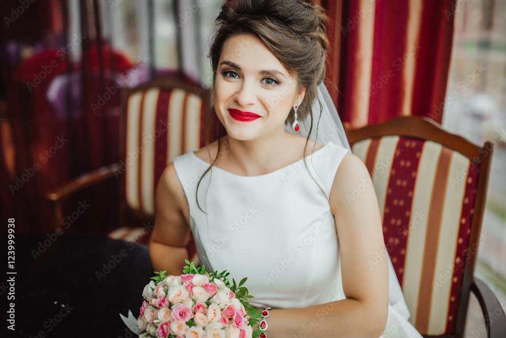 Luxury stylish wedding. Beautiful brunette. Smiling bride wedding Portrait. Red  lips makeup. Wavy hair style. Bridal bouquet of flowers. Elegant lady  sitting in red interior. Stock Photo | Adobe Stock