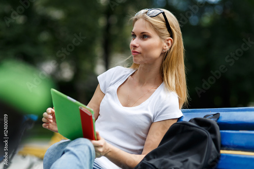 Dreamy girl with tablet in their hands sitting on bench