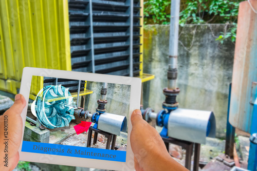 Industry 4.0 and Augmented reality for industry concept. Hand holding tablet with A/R maintenance application on screen to identify machine part repair with refrigeration container.