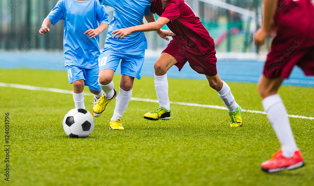 Young soccer players running towards soccer ball. Football soccer game for youth teams. Children playing soccer match Young soccer players running towards soccer ball. Football soccer game for youth teams. Children playing soccer match
