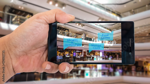Augmented reality application for retail business concept. Hand holding smart phone with A/R application on screen to finding shop in department stroe. Represent A/R application in business.