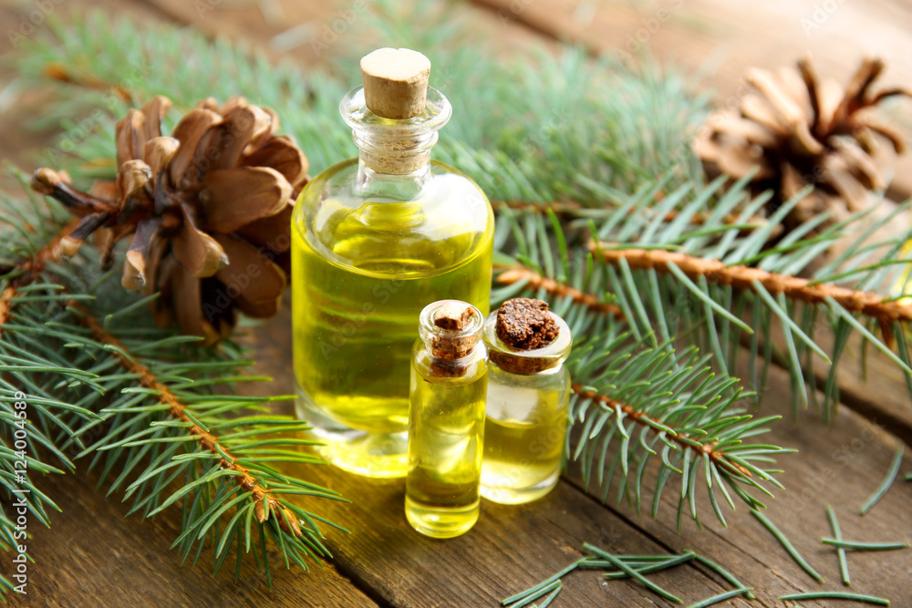 Bottles of coniferous essential oil, branches and strobiles on wooden background, close up view Bottles of coniferous essential oil, branches and strobiles on wooden background, close up view