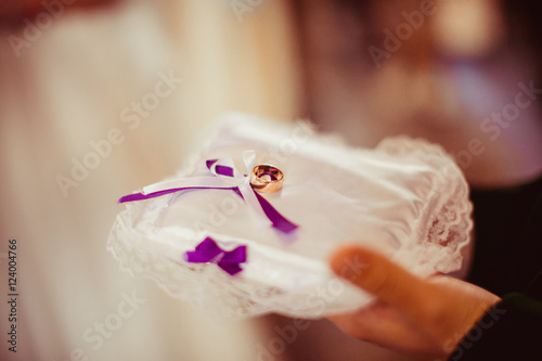 Man holds in his hands a white pillow with wedding rings on the