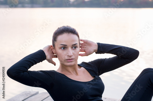 Pretty woman exercises on pier during sport training workout near river © Vera Verano