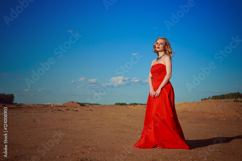 Portrait of beautiful girl in red dress on sand beach nature