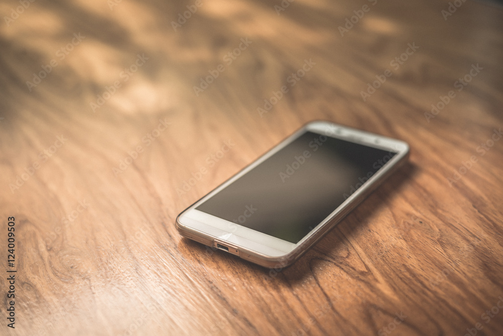 smartphone on wood table in dark tone smartphone on wood table in dark tone