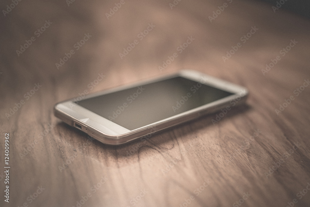 smartphone on wood table in dark tone smartphone on wood table in dark tone