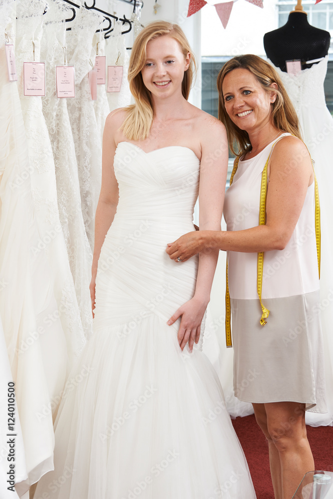 Bride Being Fitted For Wedding Dress By Store Owner