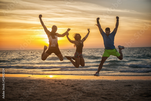 Fitness people at the beach, jumping.