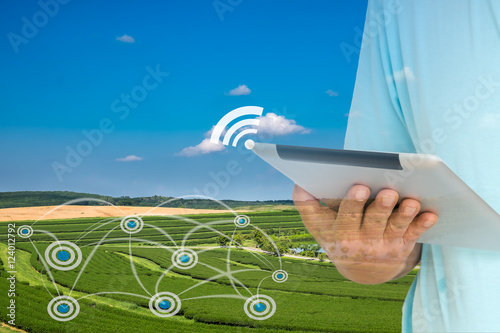 Smart Agriculture and Internet of things in agriculture concept. Farmer using digital tablet to monitor conditions from wireless sensor network in agricultural field.