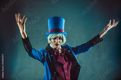 Smiling circus actor in blue tuxedo is presenting something.