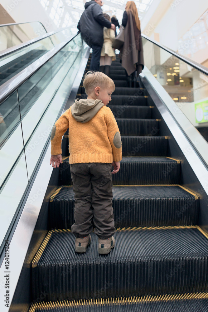 boy rides on an escalator in a big store