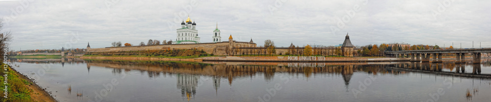Panoramic view of Pskov Kremlin. Trinity Cathedral in old fortress. Autumn cityscape wide panorama. Translation of the inscription on the bank: Russia starts here.
