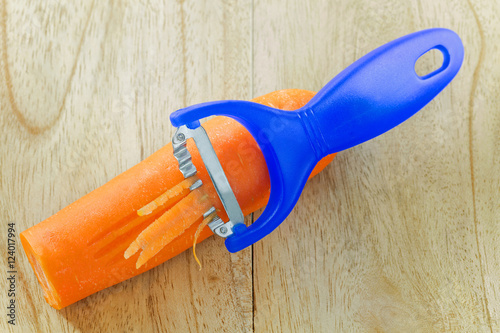 Фотография Stainless steel knife slicer tool in blue shredding carrot on a wooden backgroun