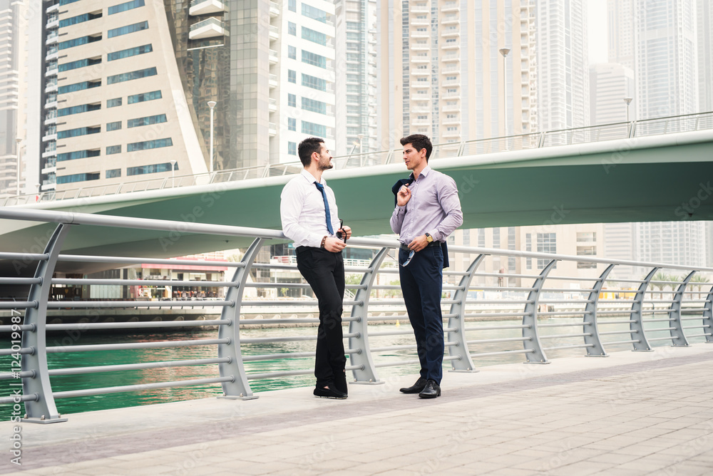 Φωτογραφία Two man standing and talking at a promenade in Dubai Marina.