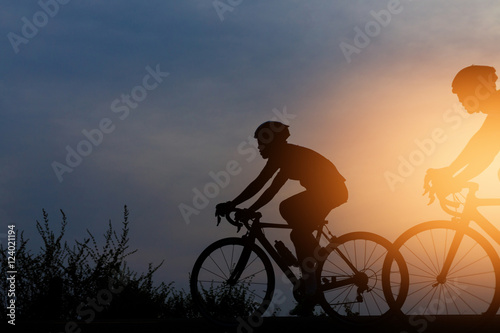 Silhouette cyclists at sunset
