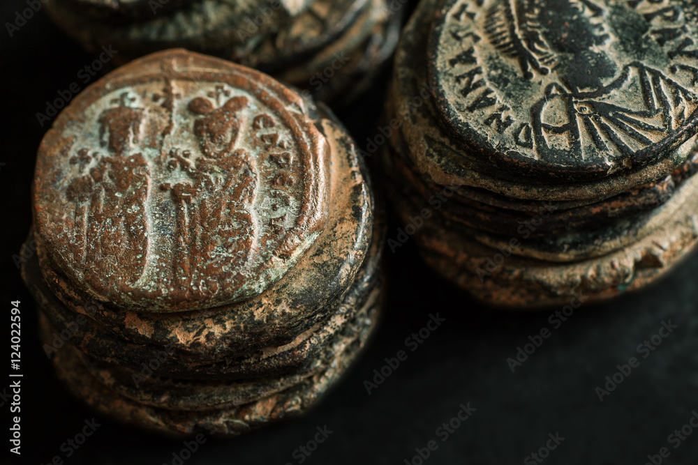 Stacks of ancient copper coins on black background