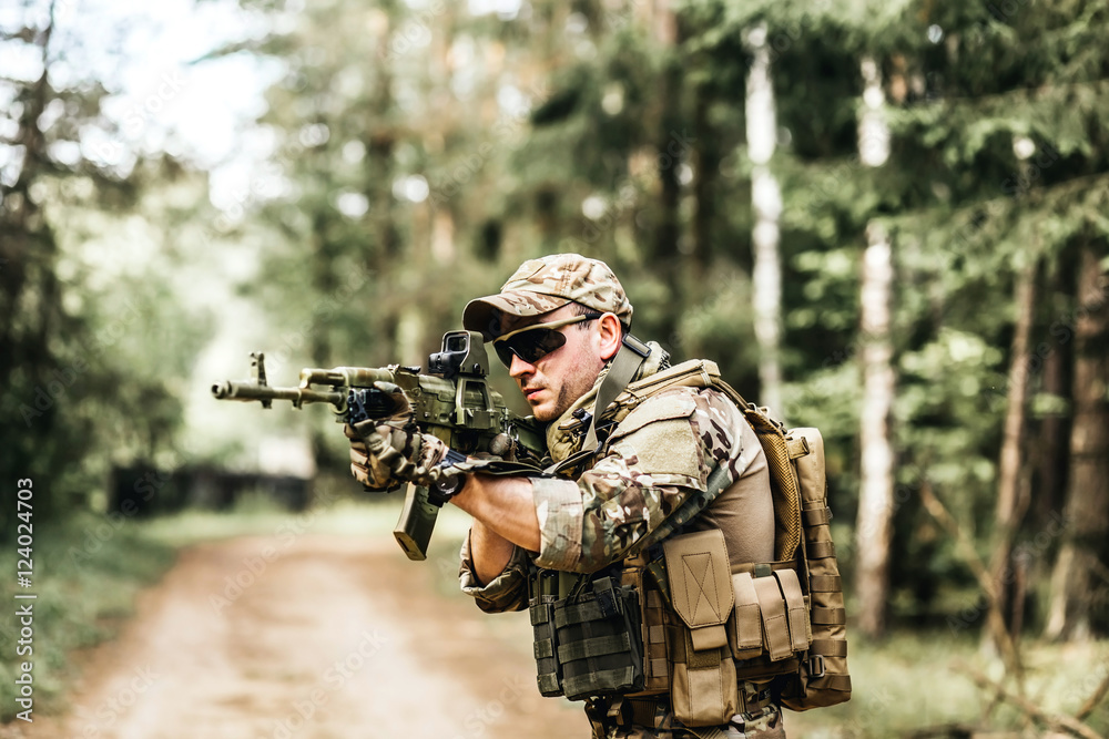 military. Armed young man in a zone of armed conflict soldier in uniform targeting with assault rifle outdoors, airsoft