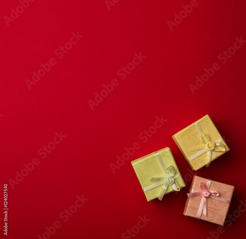 Three small gift boxes with ribbons on red background © macondos