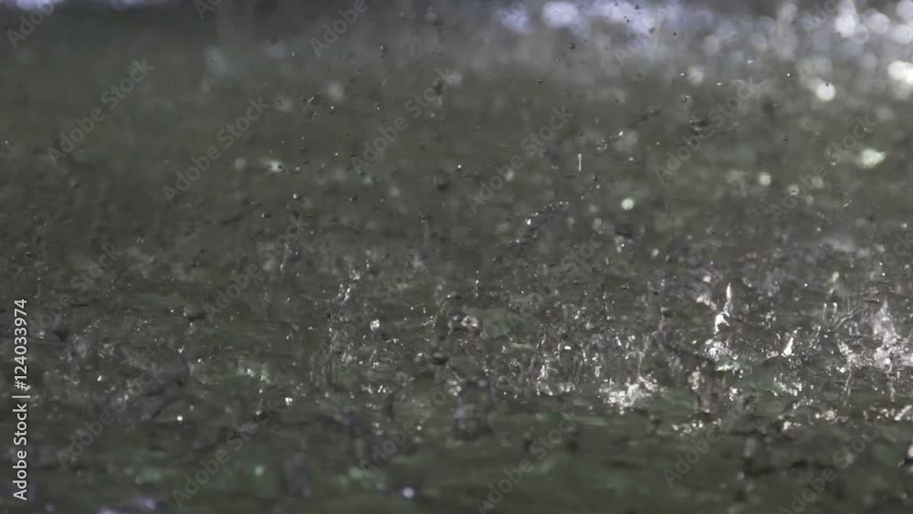 Summer downpour, raindrops splashing against water in open-air pool, slow-motion Summer downpour, raindrops splashing against water in open-air pool, slow-motion