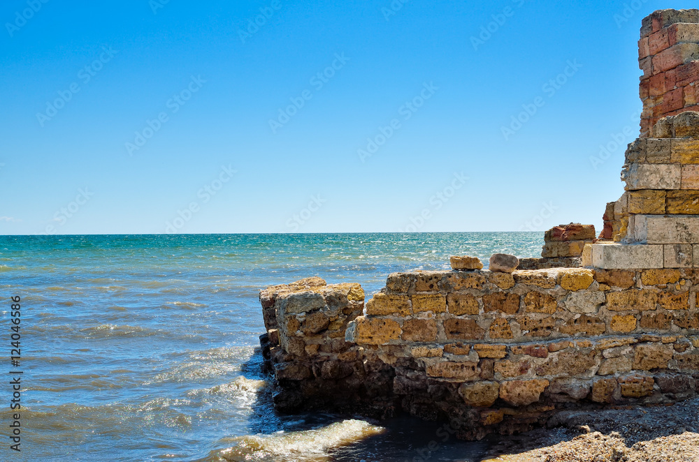 Ruins of the ancient buildings on the shore of the blue sea.
