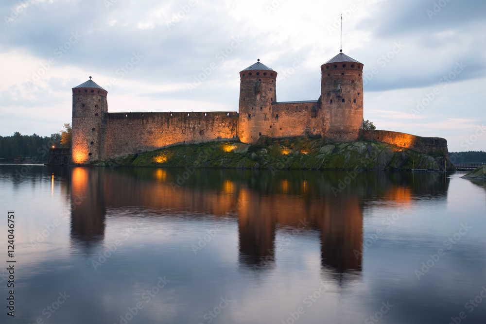 Towers of the medieval fortress Olavinlinna in the background of the cloudy sky. Twilight August in Savonlinna, Finland